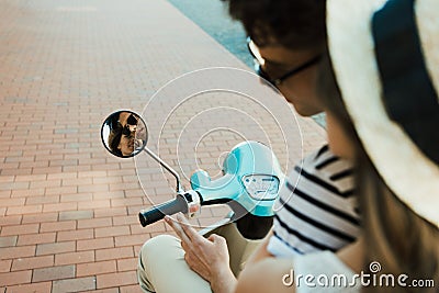 Young couple riding scooter and looking at reflection in mirror Stock Photo