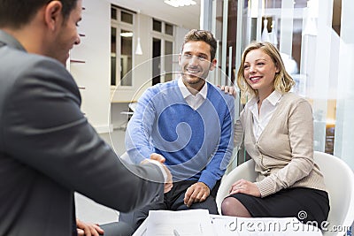 Young couple shaking hand real-estate agent in agency office Stock Photo