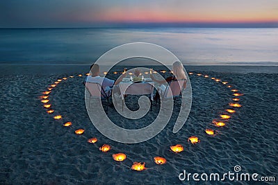 A young couple share a romantic dinner on the beach Stock Photo