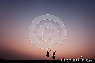 Young couple silhouette jumping outdoors at sunset dramatic Stock Photo