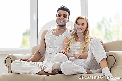 Young Couple Sit On Couch, Happy Smile Hispanic Man And Woman Hug Lovers Stock Photo