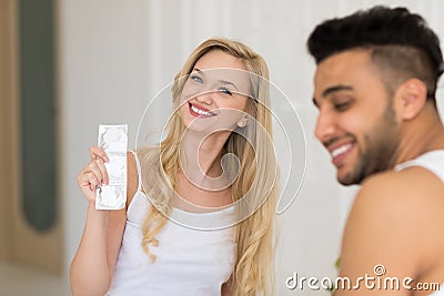 Young Couple Sitting In Bed, Smiling Woman Man Hold Condom Lovers Contraception Protection Stock Photo