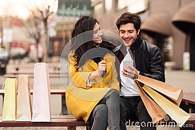 Young couple sitting on bench after shopping Stock Photo