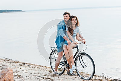 young couple sitting on bicycle on beach Stock Photo