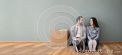 Young couple sitting on floor near box indoors. Moving into new house Stock Photo