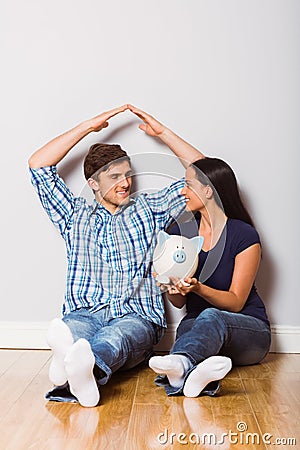 Young couple sitting on floor with piggy bank Stock Photo