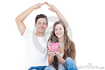 Young couple sitting on floor with piggy bank Stock Photo