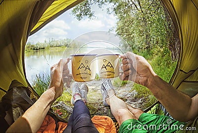 Young couple sitting in the tent and drinking tea while looking on the Desna river Stock Photo