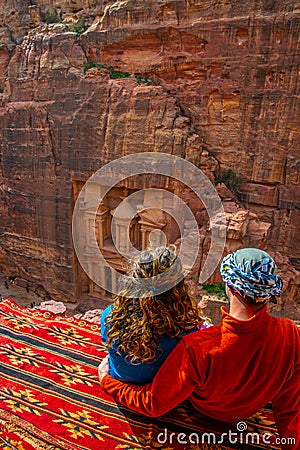 Young couple sitting at a viewpoint on Al Khazneh tomb also called Treasury at Petra, Jordan Editorial Stock Photo