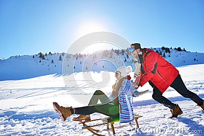 Young Couple Sledding And Enjoying On Sunny Winter Day Stock Photo