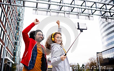 Young couple with smartphone making video for social media outdoors on street. Stock Photo