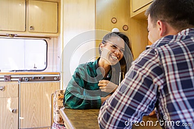 Young couple smiling and chatting while drinking beer in the caravan Stock Photo