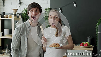 Young couple stared at the camera, standing in surprise in the kitchen at home Stock Photo