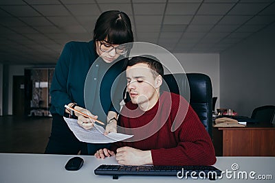 Young couple students guy and girl carefully looking at papers. Girl with glasses explaining something guy. Stock Photo
