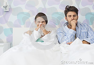 Young couple suffering from cold and flu in bed at home Stock Photo