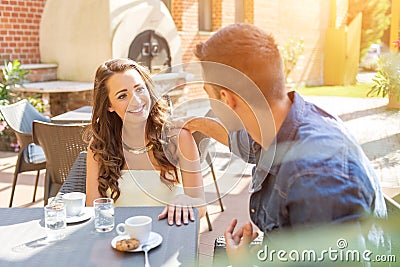 Young couple talking on the terrace of the restaurant, while eating Stock Photo