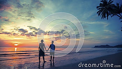 Young couple on their honeymoon standing on Sea beach at amazing sunset. Stock Photo