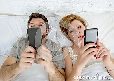 young couple using mobile phone in bed ignoring each other in relationship communication problems Stock Photo