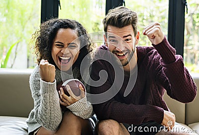 Young couple watching american football at home Stock Photo