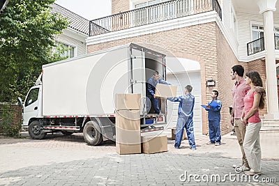 Young couple watching movers move boxes from the moving van Stock Photo