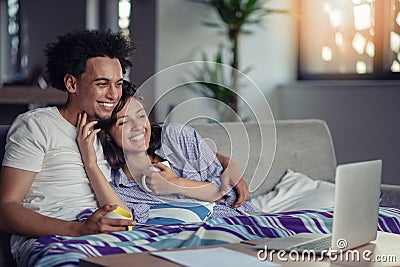 Young couple watching a movie on their laptop in bed Stock Photo