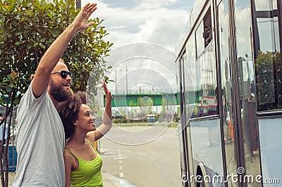 Young couple waving goodbye to their friends on the bus Stock Photo