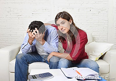 Young couple worried home in stress wife comforting husband accounting debt unpaid bills bank papers expenses Stock Photo