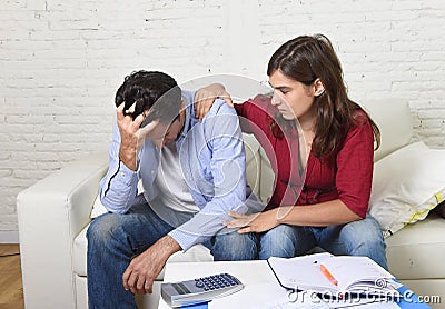 Young couple worried home in stress wife comforting husband accounting debt unpaid bills bank papers expenses Stock Photo