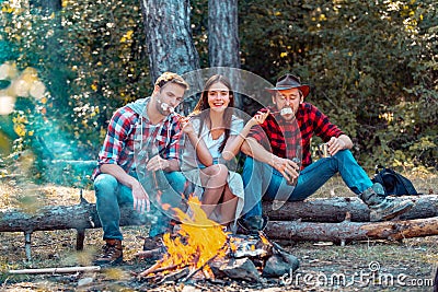 Young couples having picnic in woods. Young people having a camping. Company friends enjoy relaxing together in forest Stock Photo