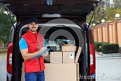 Young courier checking amount of parcels in delivery van Stock Photo