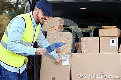 Young courier checking amount of parcels in delivery van Stock Photo