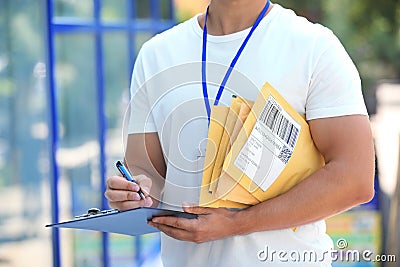 Young courier with padded envelopes and clipboard, closeup. Delivery service Stock Photo