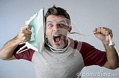 Young crazy desperate and frustrated man doing housework holding iron Stock Photo