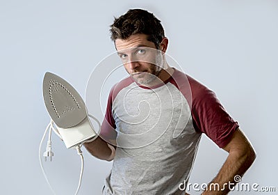 Young crazy desperate and frustrated man doing housework holding iron Stock Photo