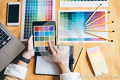 Young creative Graphic designer using graphics tablet to choosing Color swatch samples chart for selection coloring with work too Stock Photo