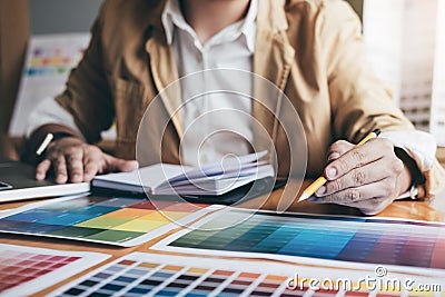 Young creative Graphic designer using graphics tablet to choosing Color swatch samples chart for selection coloring with work Stock Photo