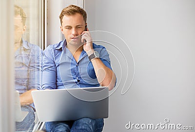 Young creative man working with computer while talking on phone Stock Photo