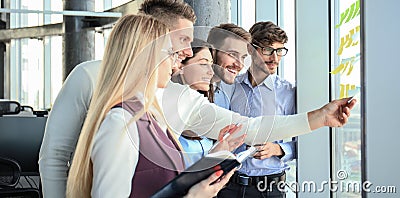 Young creative startup business people on meeting at modern office making plans projects with post stickers on glass Stock Photo