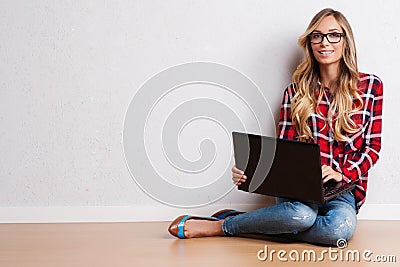 Young creative woman sitting in the floor with laptop./ Casual b Stock Photo