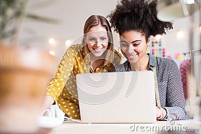 Young creative women with laptop in studio, startup business. Stock Photo