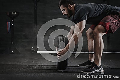 Young cross fit athlete preparing barbell for lifting weight at the gym. Barbell magnesia protection.Handsome man doing functiona Stock Photo