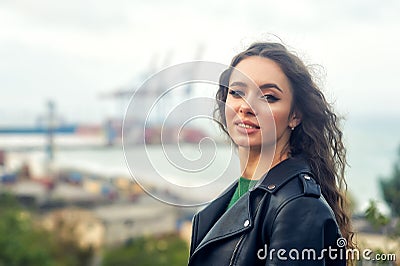 Young curly haired woman in fashionable leather jacket Stock Photo