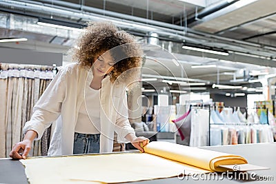 young and curly saleswoman measuring yellow Stock Photo