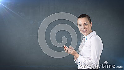 Young cute businesswoman close up portrait holding mobile phone in her hands and watching it. Isolated studio background Stock Photo