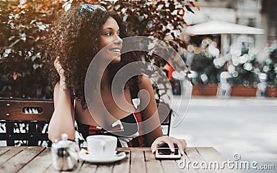 Curly laughing woman in a street cafe with the cellphone Stock Photo