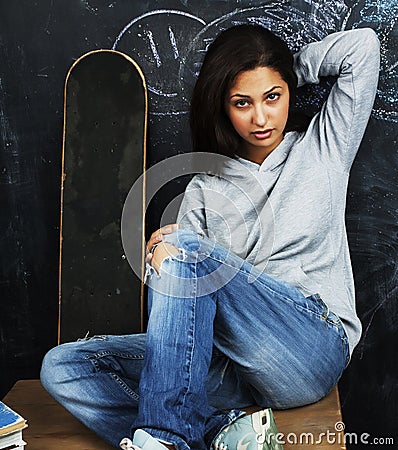 Young cute teenage girl in classroom at blackboard seating on ta Stock Photo