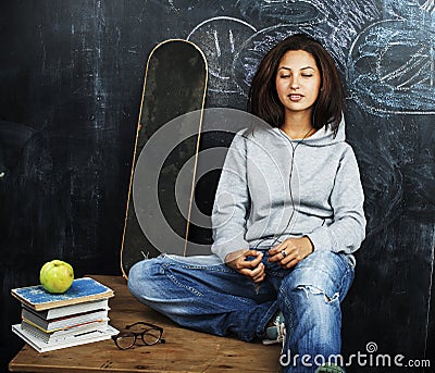 Young cute teenage girl in classroom at blackboard seating on ta Stock Photo