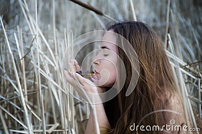 Young cute woman kisses a frog, enchanted prince like in fairy tale frog prince, copy space Stock Photo