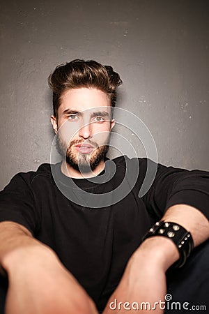 A young dark-haired man with a beard sits on the floor and throws papers and documents into the air. Human emotions Stock Photo