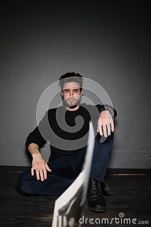 A young dark-haired man with a beard sits on the floor and throws papers and documents into the air. Human emotions Stock Photo